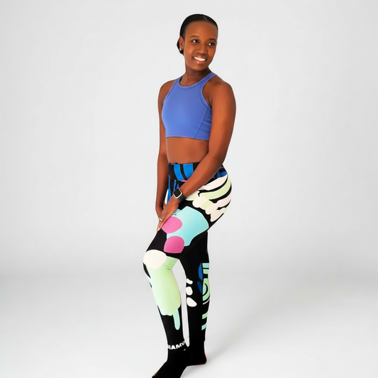 A woman wearing IHAMORA high-waist leggings with a vibrant bold print, consisting of geometric shapes in multiple colors. Women’s activewear XS–4XL
