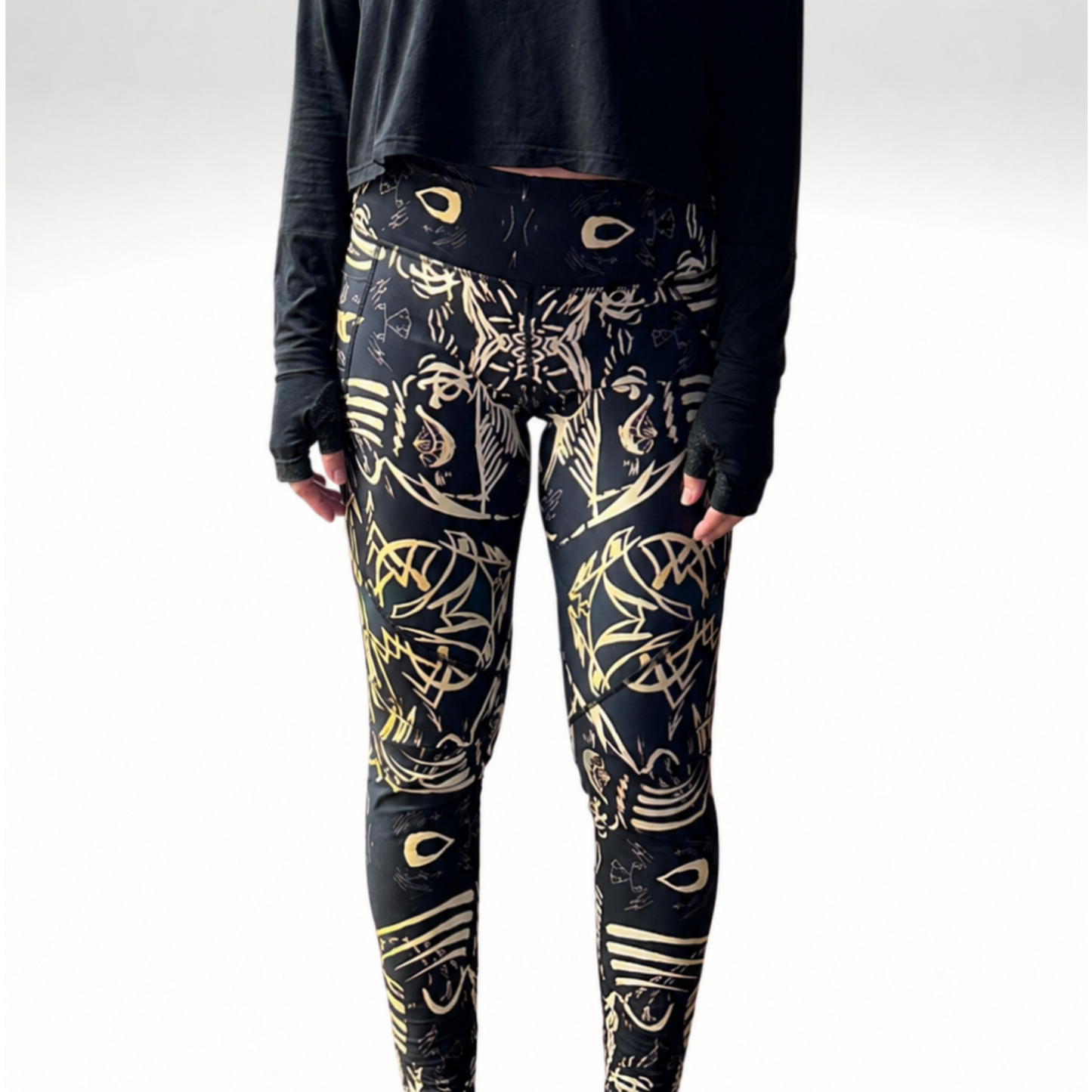 Person wearing black long-sleeve top and patterned leggings on a white background