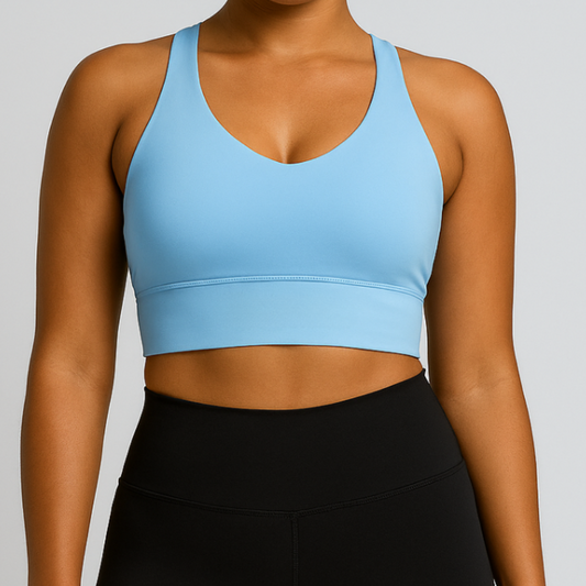 Woman wearing a light blue sports bra and black leggings on a gray background