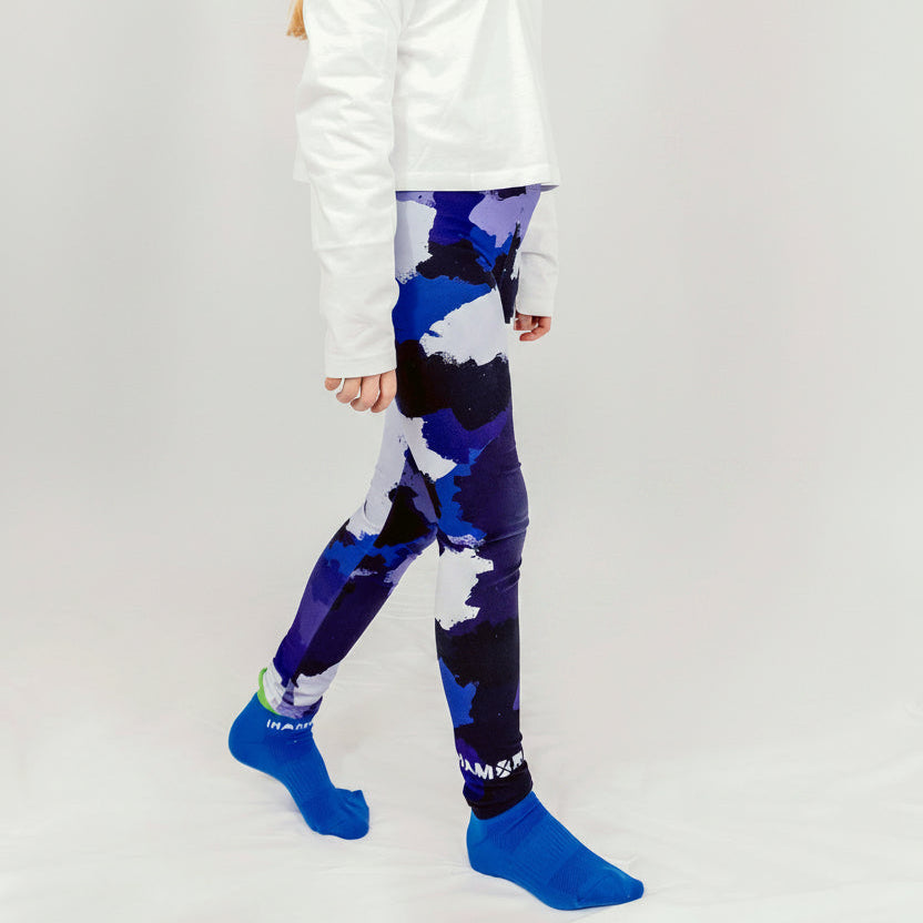 A girl wearing a white hoodie and blue camo leggings, standing against a white background, Girl wearing IHAMORA Blue Camo seamless leggings with bright blue camo pattern.