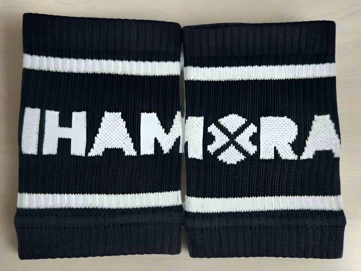A pair of black essentials sports wristbands with the IHAMORA logo in white.