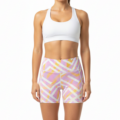 Woman wearing a white sports bra and patterned shorts on a white background
