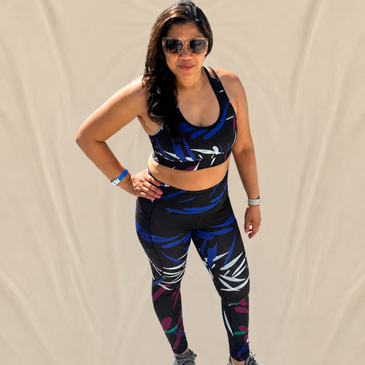 Woman wearing a colorful sports bra and leggings set with gray sneakers against a beige background
