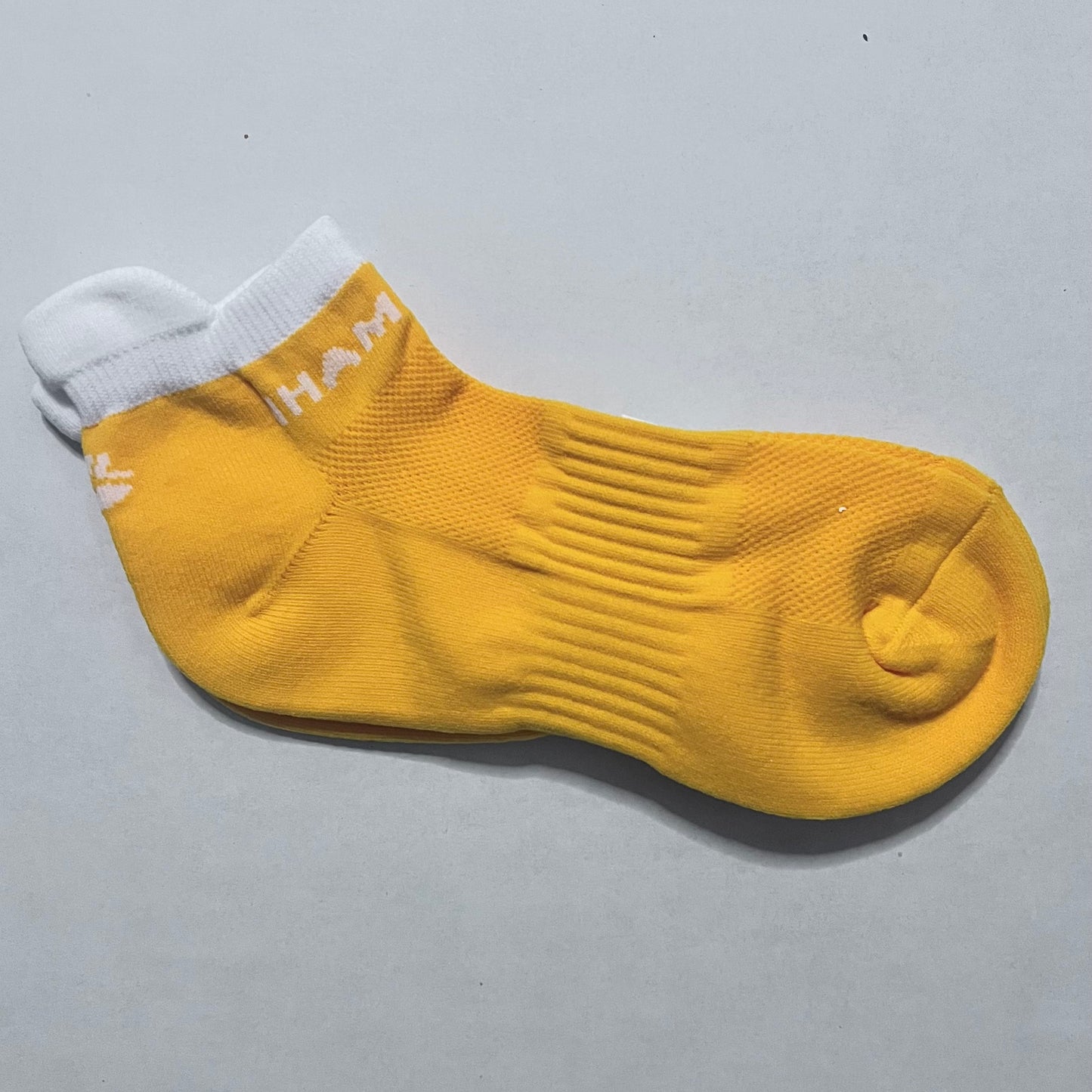 Yellow sock with white cuff on a gray background