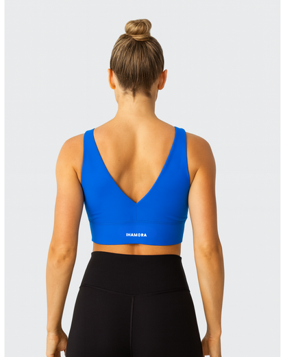 Woman wearing a V NECK blue sports bra with 'IHAMORA' branding on a gray background