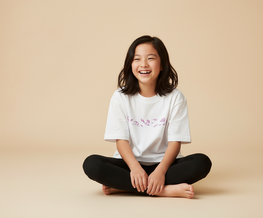 Girl wearing A white crew neck t-shirt with a pink graphic print in the center, displayed against a pink background.