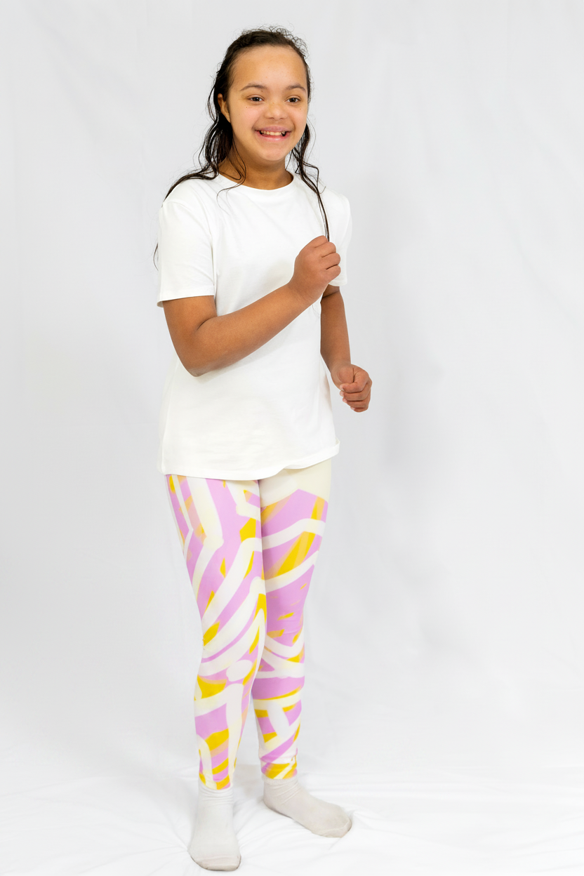 girl wearing a white t-shirt and colorful leggings on a plain background