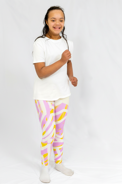girl wearing a white t-shirt and colorful leggings on a plain background