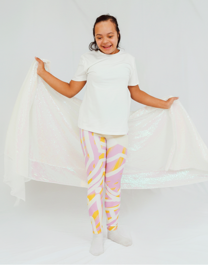 girl wearing a white shirt and colorful pants holding a white fabric against a white background