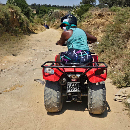 Woman riding a red ATV on a dirt road with greenery around wearing high-waisted bamboo gym shorts by IHAMORA